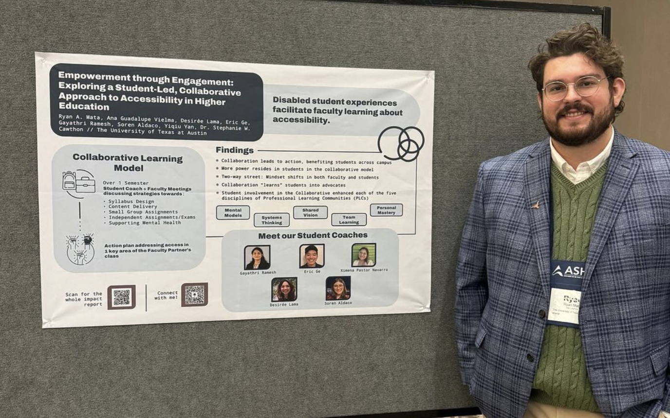 Ryan A. Mata Standing in front of poster in a blue plaid suit jacket with a green sweater underneath and Khaki pants. He has brown short wavy hair and a beard.